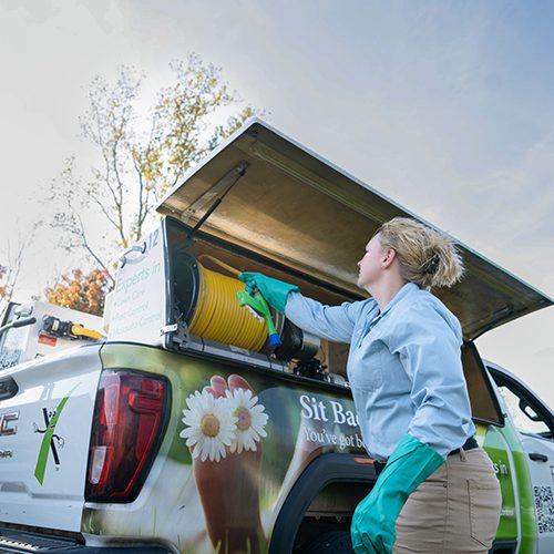 Lawn care technician pulling hose out of the back of a lawn care truck.