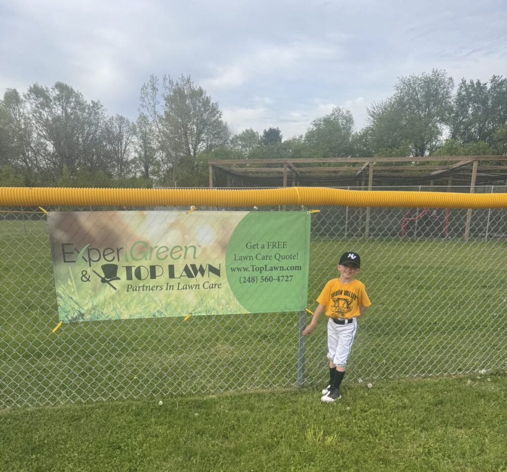 T-Ball Player next to Top Lawn Banner
