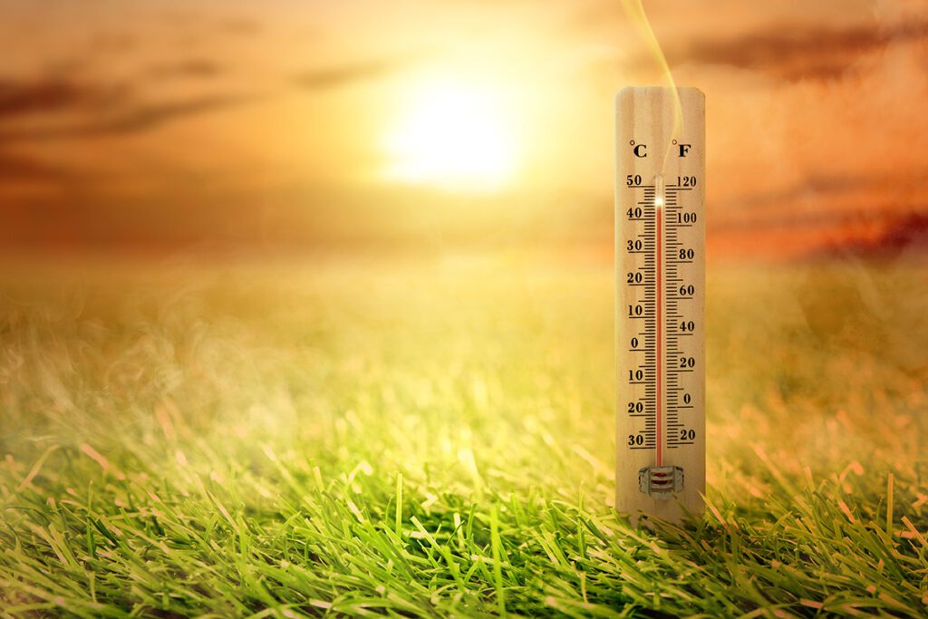 Thermometer with high temperature on the grass with glowing sun