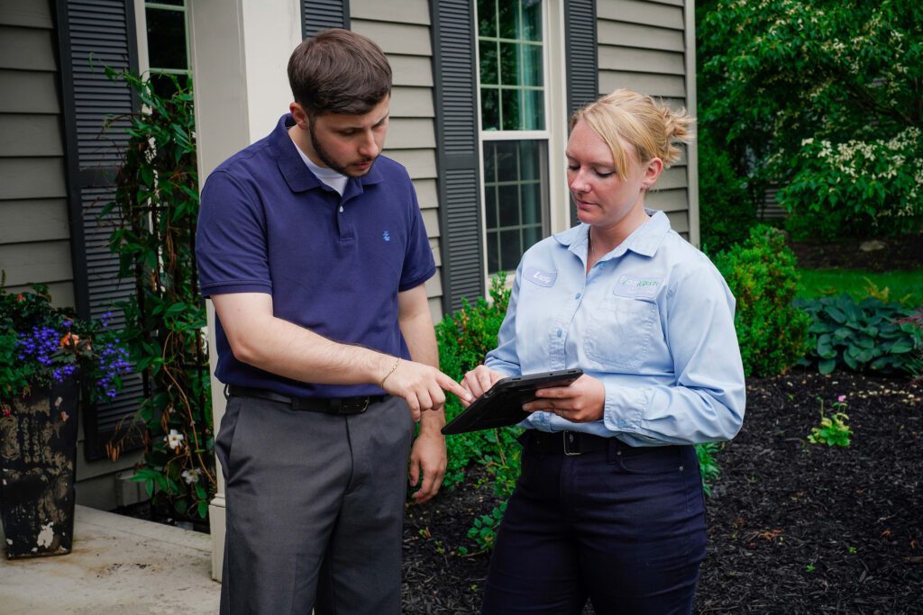 Customer pointing to tablet with lawn care technician
