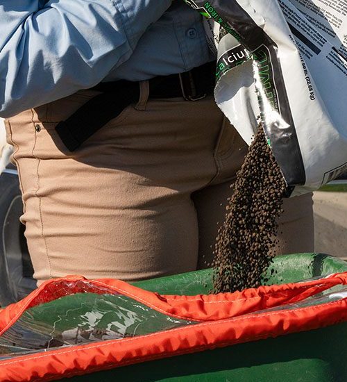 Pouring fertilizer Technician pouring fertilizer into spreader